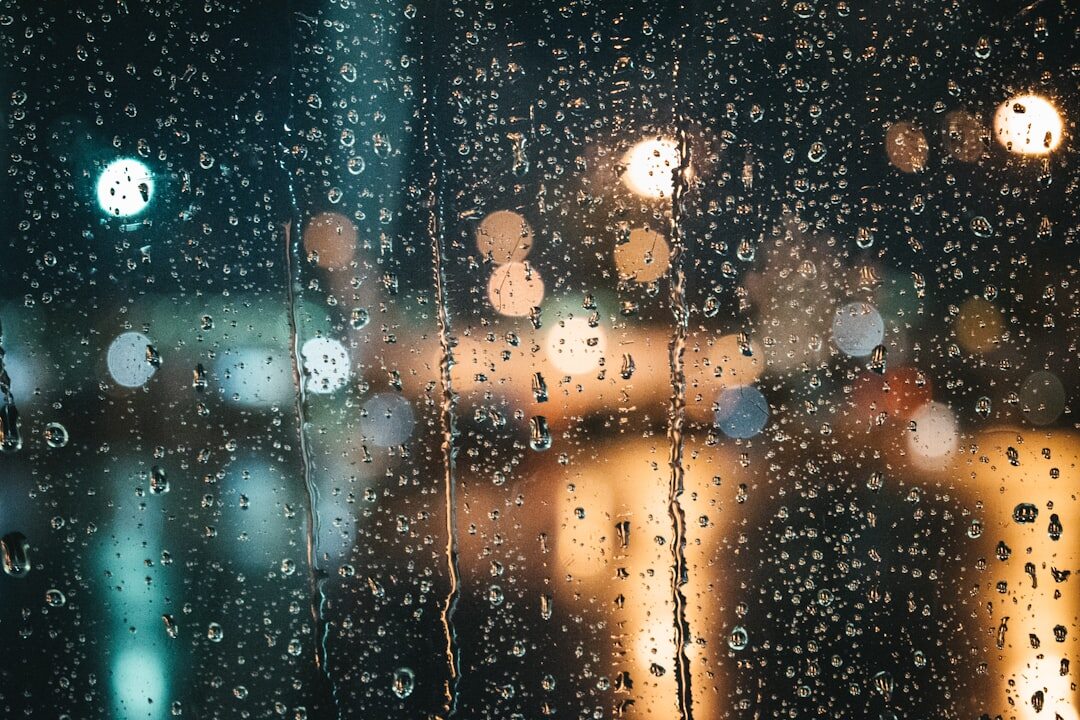 Raindrops on a window with blurred city lights at night